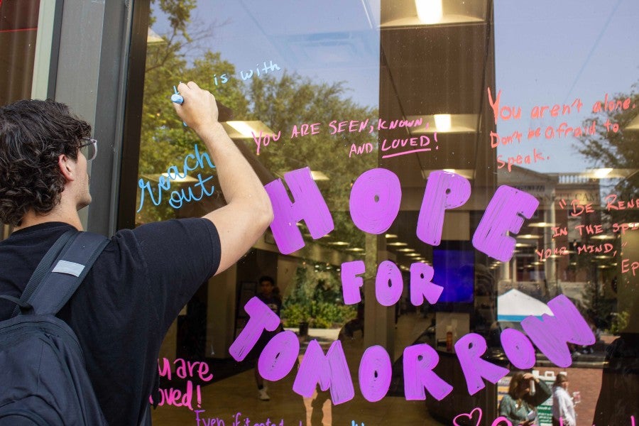 Student signing "Hope for Tomorrow" sign on Suicide Awareness Day on campus
