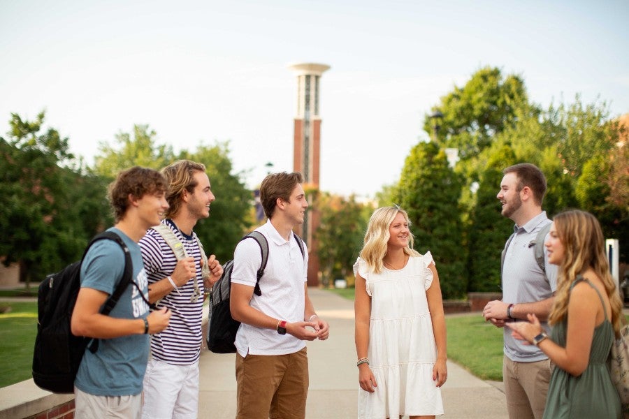 Students talking on campus in front of the Bell Tower