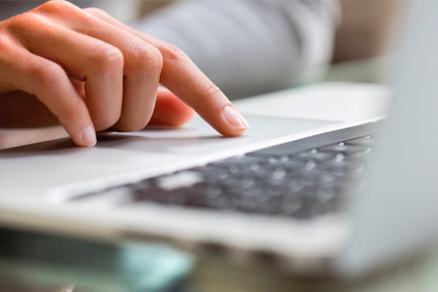 A person's hand working on a laptop computer keyboard.