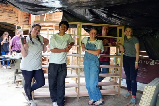 Students posing in front of book shelf they built for the Host Partners. 