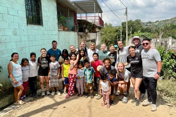 Team posing with locals after a soccer game in the streets.