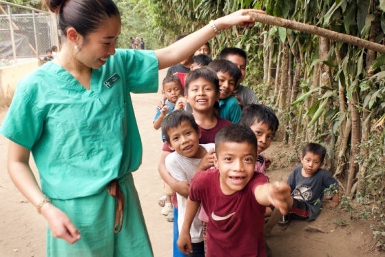 Nursing student smiling with a group of local children.