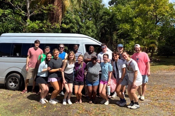 Nevis team gathered together in front of a beautiful forest backdrop. 