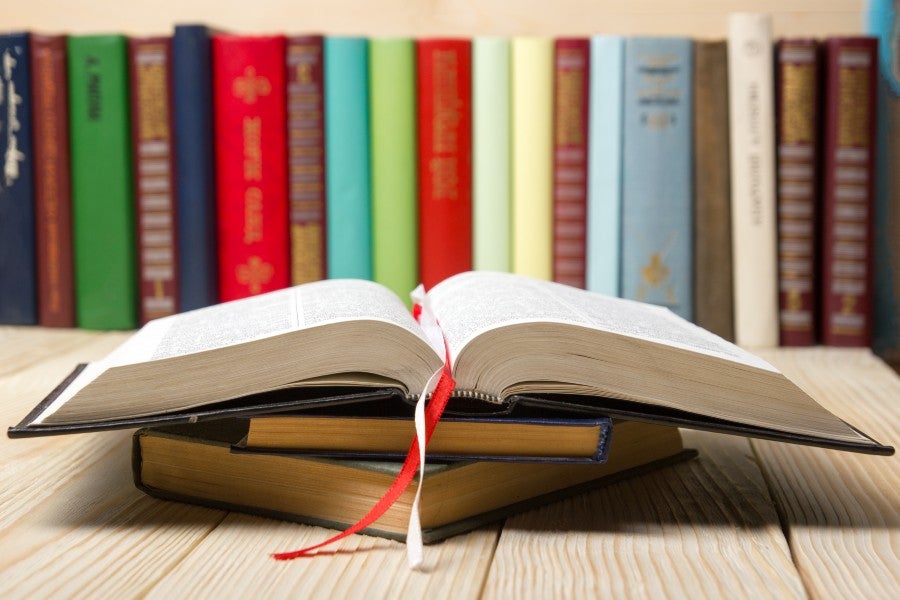 An open book in front of a shelf of books