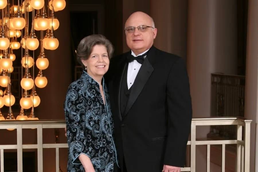 Nancy and Roger Davis in formal attire standing near a railing. 