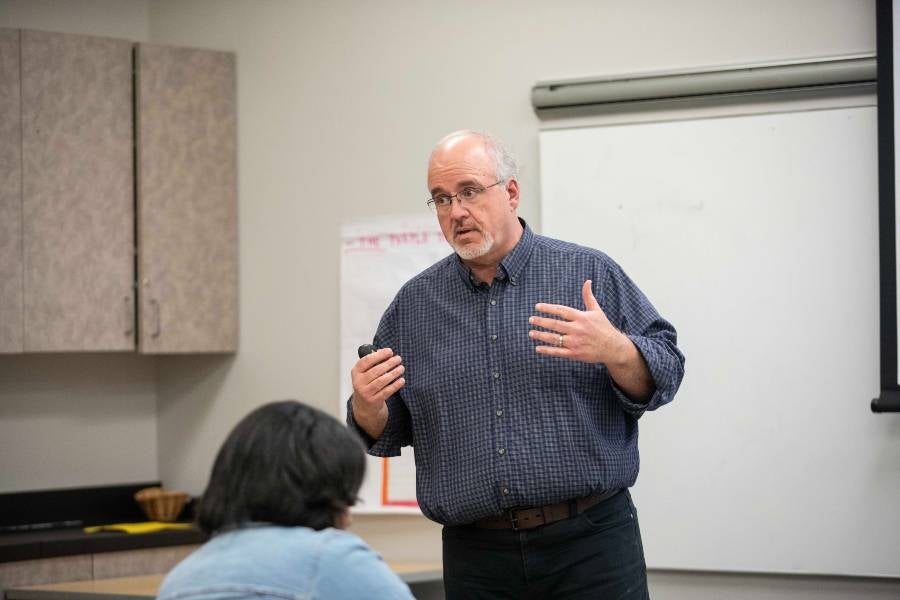 Associate Provost Trace Hebert standing in front of a white board teaching. 