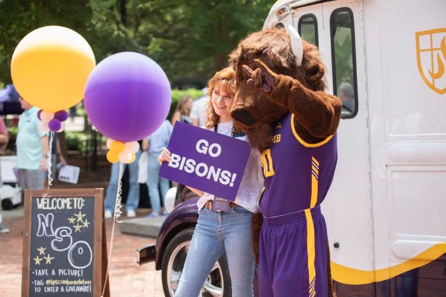 a new student posing with Lou, Lipscomb's mascot, at an event in Bison Square