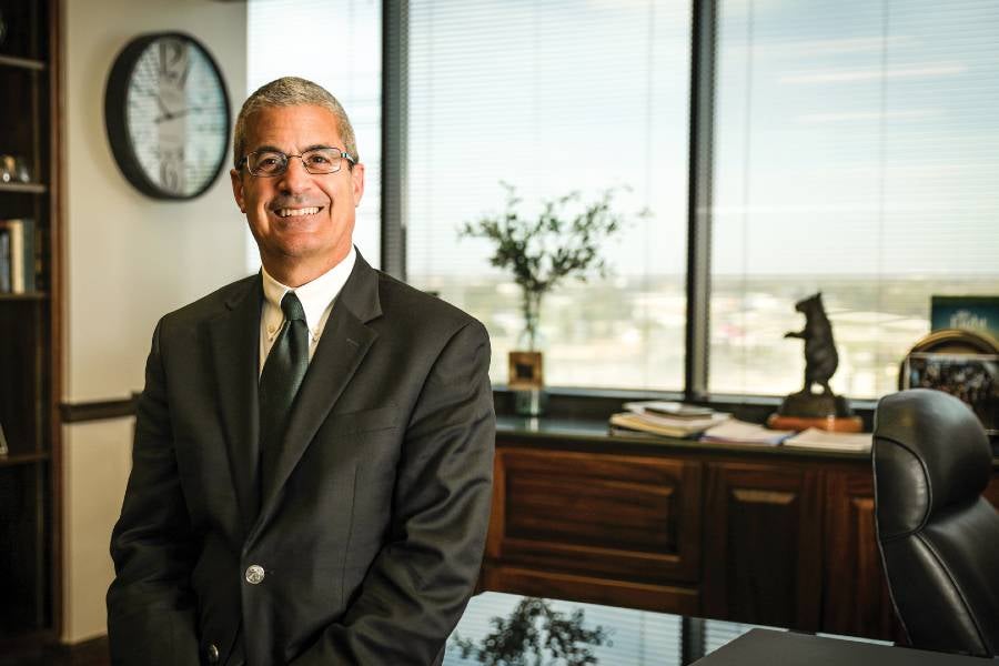 David Rosselli sitting at a desk in his office with a window behind him. 