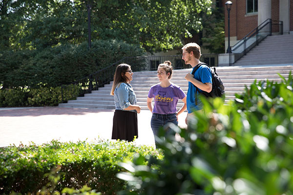 Three students standing outside and talking