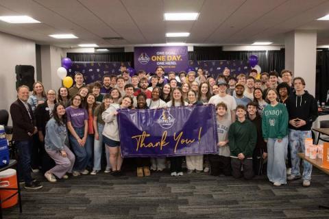 Group of students standing with a thank you sign in Giving Day central. 