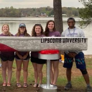 students in front of their canoe at the concrete canoe competition