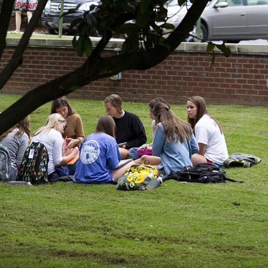 Students sit outside in the grass during a Breakout Chapel session