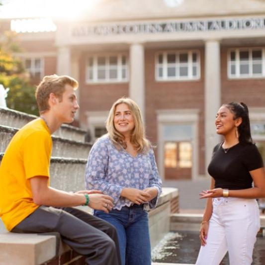 Three students talking to each other before class