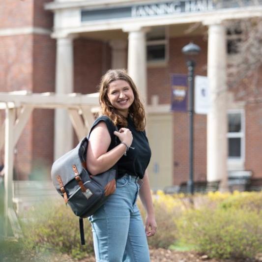 Student veteran standing in front of campus and smiling