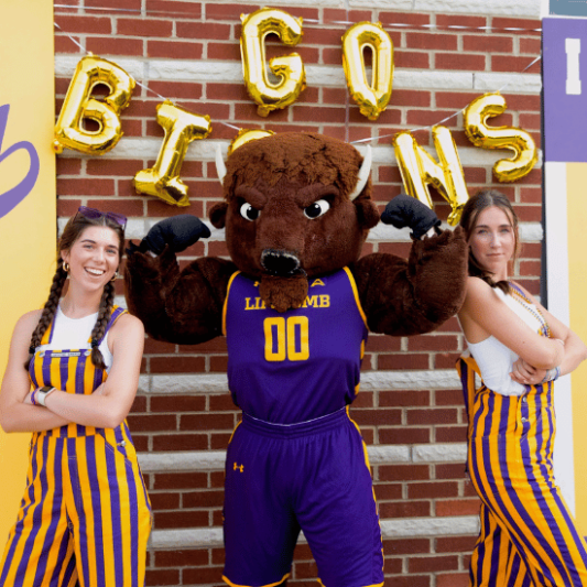 Two Lipscomb students in purple and yellow striped overalls