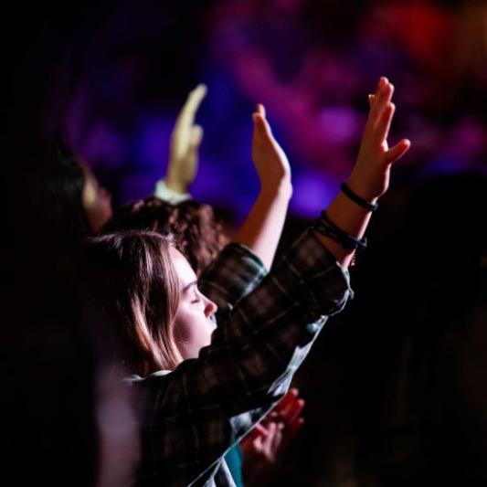 Student with hand raised in worship