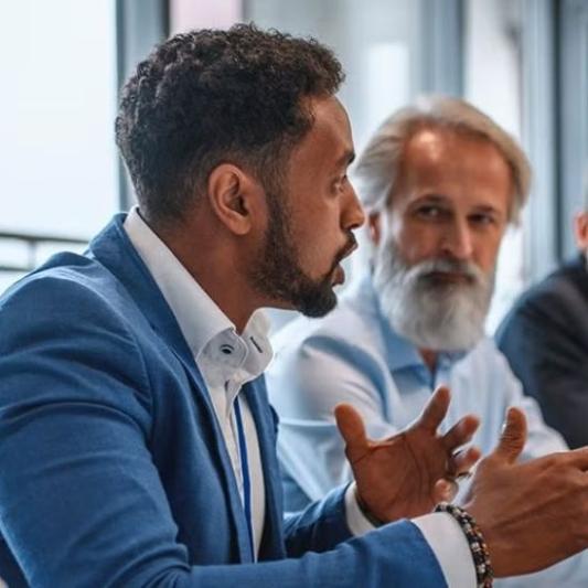 Two men having a roundtable discussion in a professional meeting.