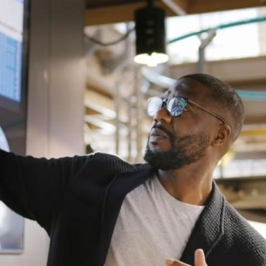 A man pointing to something on a presentation screen during a meeting.