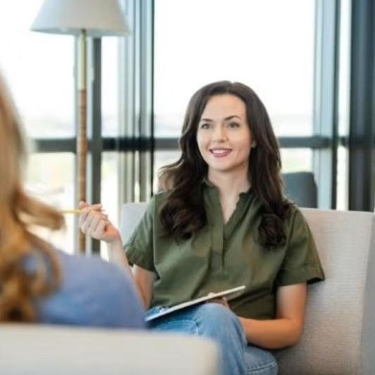 Student facing another woman talking to her in a office.