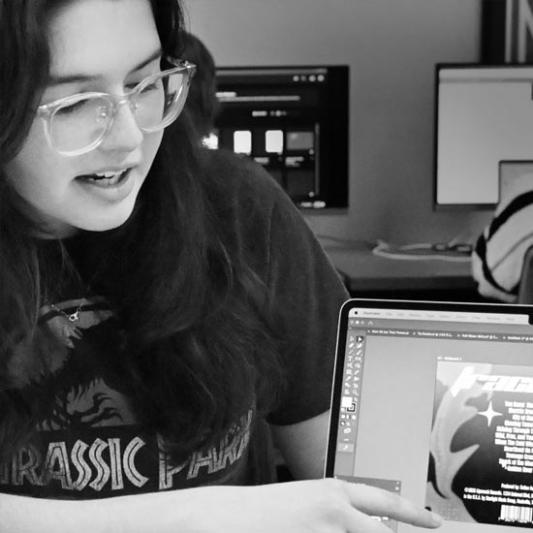 Student pointing at their computer, showing Adobe Illustrator