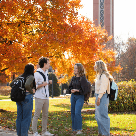 Group of student chatting by the belltower in the fall
