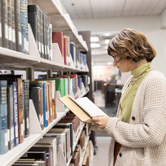 Female student looking at books in Beaman Library. 