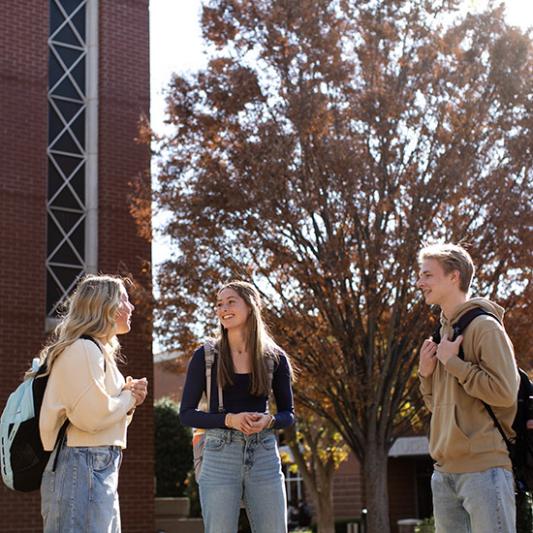 Three students standing by the Bell Tower. 