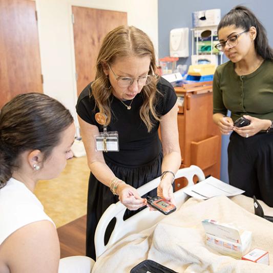 Faculty member with two students in the nursing simulation lab. 