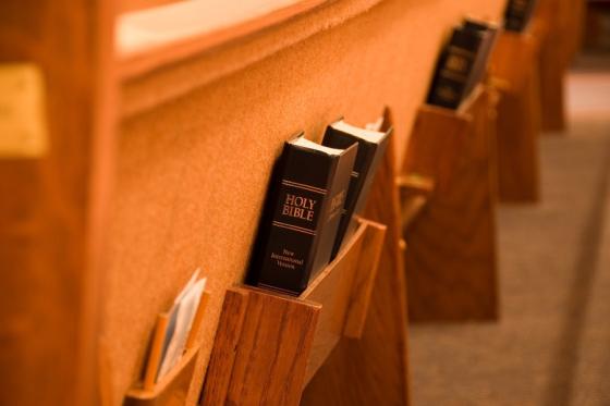 Back of a church pew with a Bible in the holder