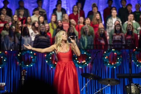 Ellie Holcomb singing with a student choir in the background. 