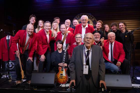 Members of the Delta NaNaNa reunion band on stage posing with former Dean Carl McKelvey