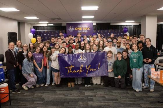Group of students standing with a thank you sign in Giving Day central. 
