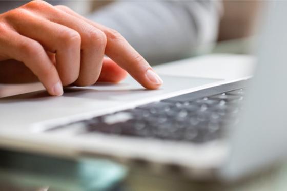 A person's hand working on a laptop computer keyboard.