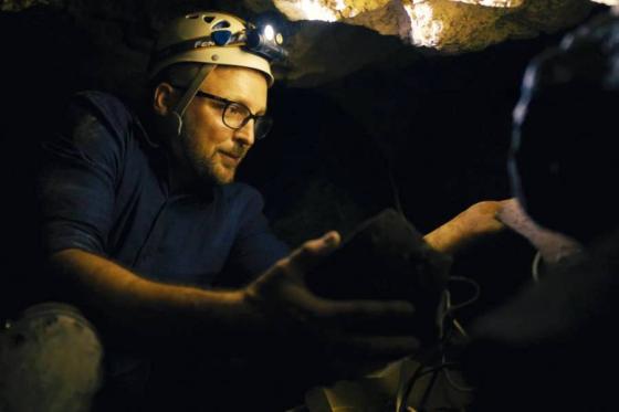 Lipscomb professor Chris McKinny on an excavation site wearing a hard hat and head lamp in a scene from the film. 