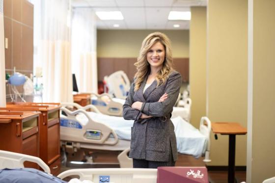 Chelsia Harris standing in front of nursing lab beds. 