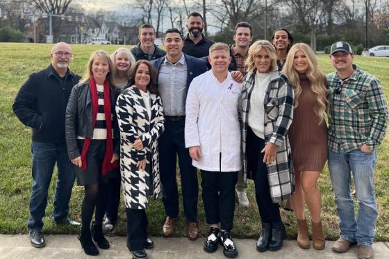 Trever Facey, in white coat, surrounded by family and friends at nursing pinning ceremony. 