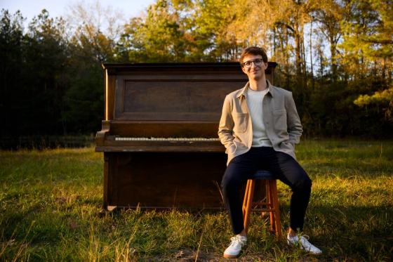 Hudson Tucker sitting on a piano that is outside. 