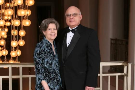 Nancy and Roger Davis in formal attire standing near a railing. 