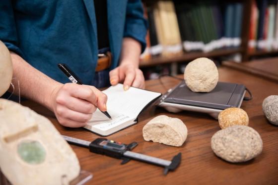 ground stones being measured and documented in the archaeology room on campus