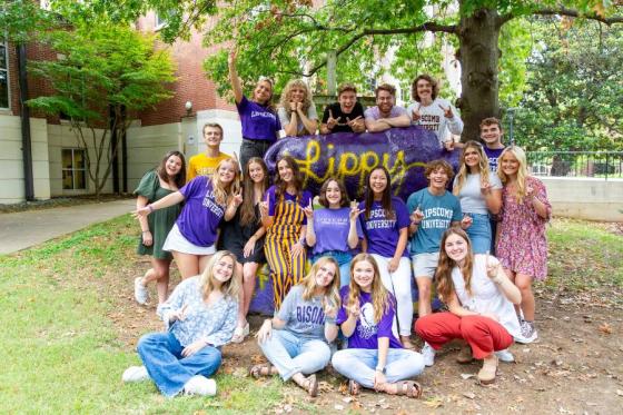 Lipscomb students surrounding the Bison wearing purple and gold clothing and looking school spirited.
