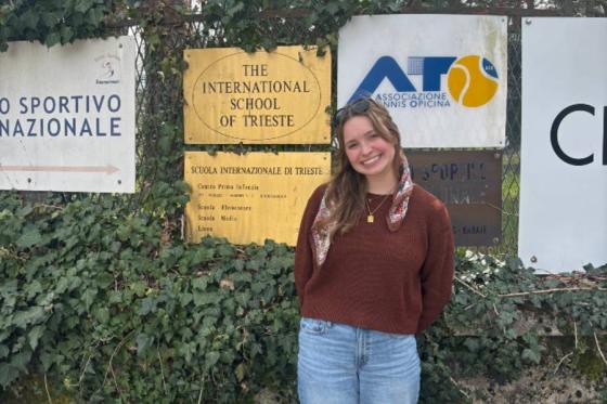 Allison Meadows standing in front of a school sign in Italy. 