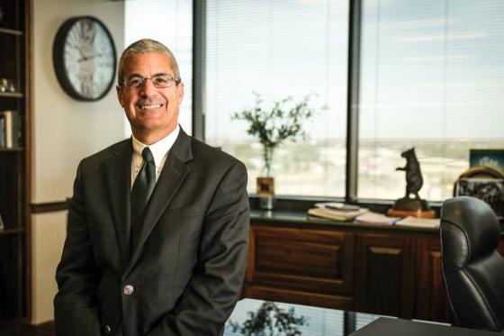 David Rosselli sitting at a desk in his office with a window behind him. 