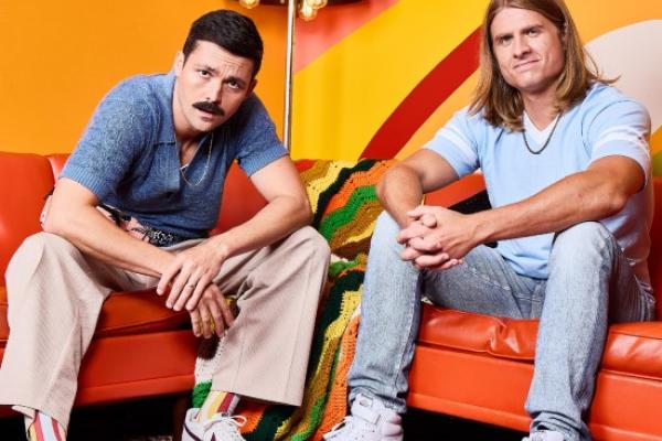 Austin & Colin posing on orange couches